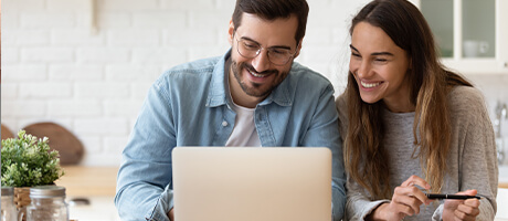 young couple smiling and looking at a computer