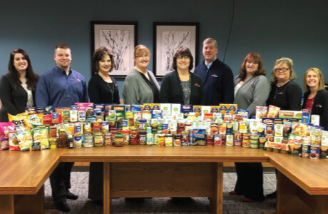 Group of Employees standing behind stacks of pantry items to be donated