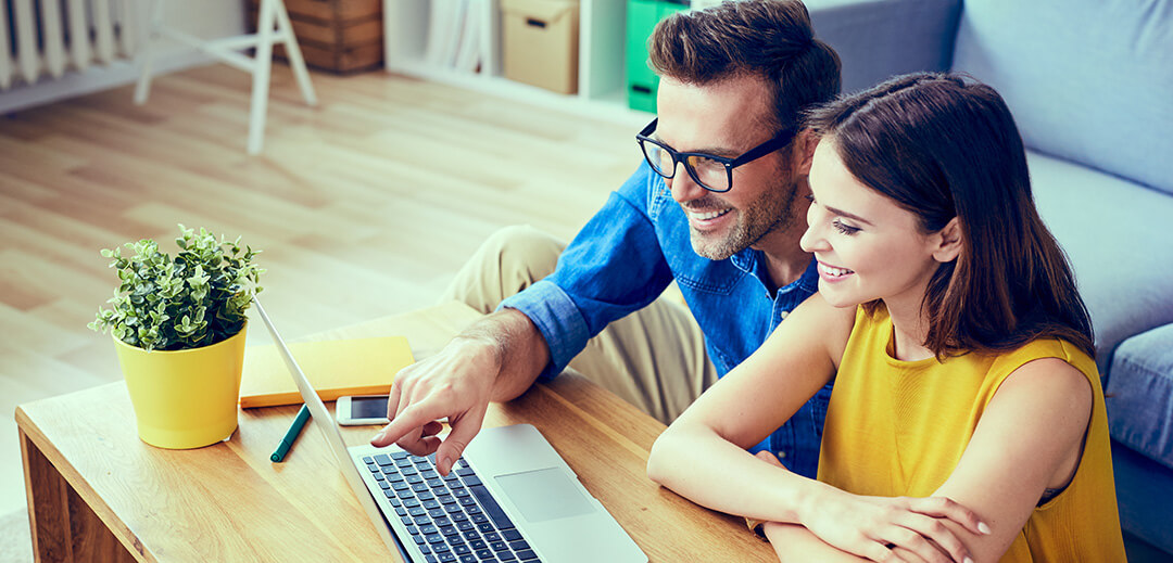 couple sitting on floor in front of laptop