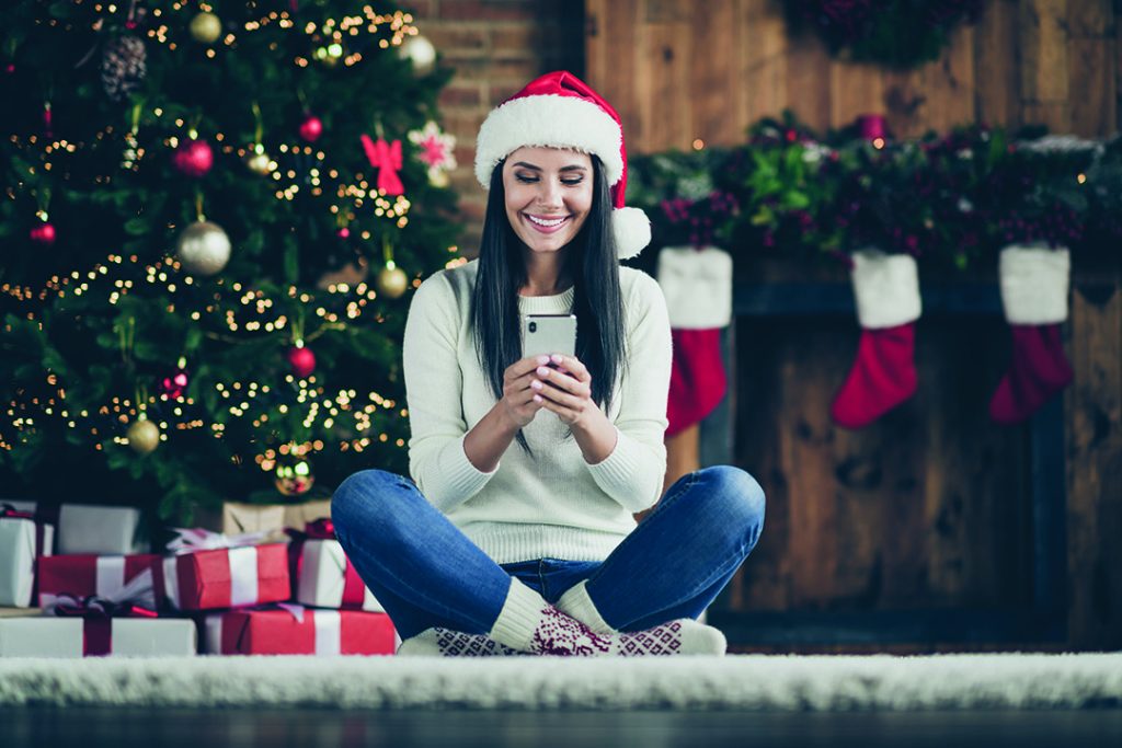 woman on phone in front of christmas tree
