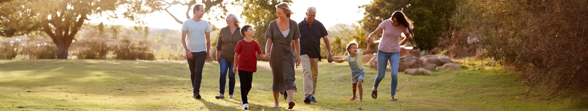 Multi-Generation Family Walking In Countryside Against Flaring Sun