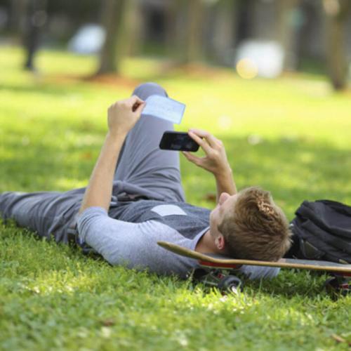 man laying on the ground taking a picture of a check with his phone